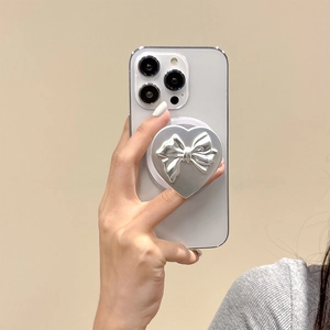Macro detail of silver heart-shaped phone grip with relief bow on a smartphone