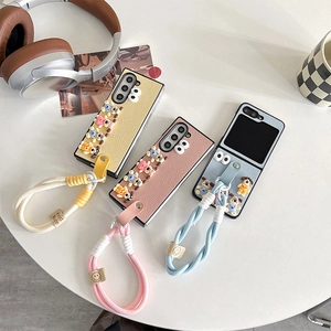 Close-up of leather foldable phone cases with cute dog charms and braided straps