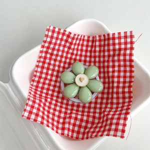 Close-up of light green flower phone grip with heart detail on red checkered cloth