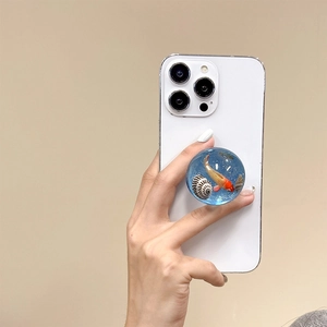 Detail view of 3D resin phone grip with goldfish and seashell inside on white smartphone