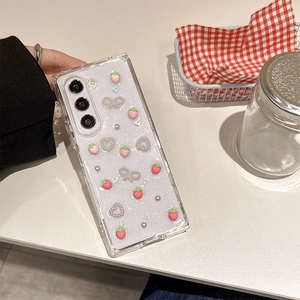 Detail of glitter phone case featuring 3D strawberry, pearl hearts and silver bows