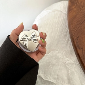 Detail view of heart-shaped magnetic phone grip with 3D silver bow and metallic finish