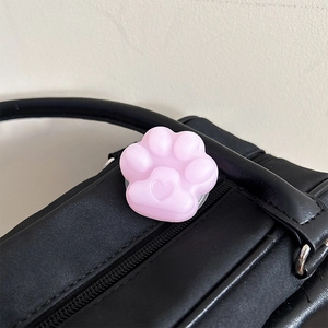 Detailed view of a cute pink cat paw phone grip with heart detail on black leather bag