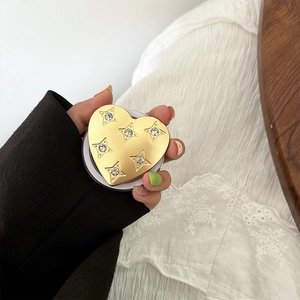Close-up of heart-shaped gold phone grip with sparkling star rhinestones in hand