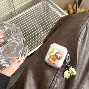 Gros plan d'un étui AirPods transparent avec des charmes 3D pistache et cacahuète
