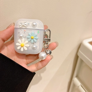 Dettaglio della custodia AirPods glitterata con fiori, perle e ciondolo a cuore