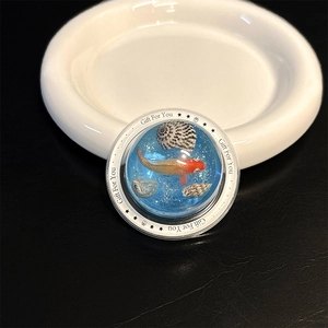 Detailed close-up of a creative round phone grip featuring a red goldfish and seashell