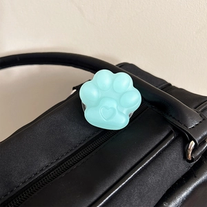 Close-up of mint green cat paw phone grip with heart detail on a black leather bag
