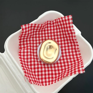 Detailed view of an abstract gold geometric phone stand on a red plaid background