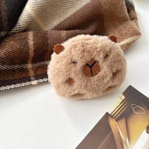 Détail d'un charmant pendentif en peluche capybara marron sur un fond blanc épuré