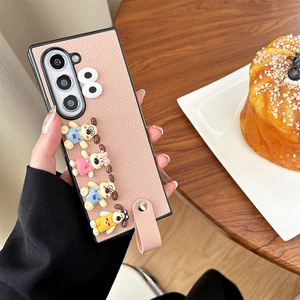 Detailed view of pink leather phone case with 3D cartoon puppies and hand strap.