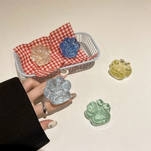 Detail von glitzernden Katzenpfoten-Handyhaltern aus pastellfarbenem Harz auf Tisch