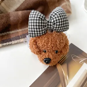 Détail macro du charm caniche en peluche avec fourrure bouclée et nœud à carreaux noir et blanc