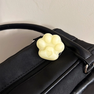 Close-up of a cream yellow cat paw phone grip with heart detail on a black leather bag