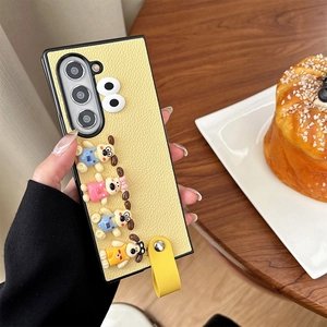 Detail view of yellow textured leather phone case with cute 3D cartoon dog charms and strap
