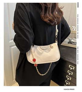 Detail of off-white lychee leather bag with golden chain and red strawberry charm