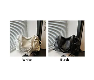 Detail view of large faux leather tote bags in white and black colors with dual straps
