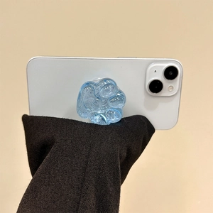 Detailansicht der glitzernden blauen Katzenpfote-Handyhalterung auf weißem Smartphone