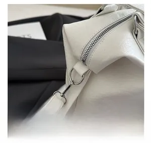 Macro shot of silver metal hardware and lychee grain texture on white leather tote bag