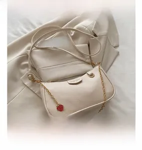 Detail of beige lychee leather bag with gold chain and red strawberry charms