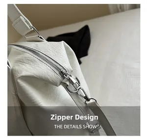 Detailed close-up of smooth silver zipper and litchi texture on white shoulder bag