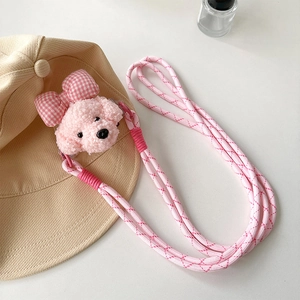 Détail de breloque chien en peluche rose et lanière de téléphone tressée avec nœud