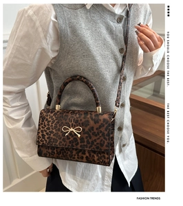 Detail showing leopard print texture with gold bow hardware and round handle on a bag