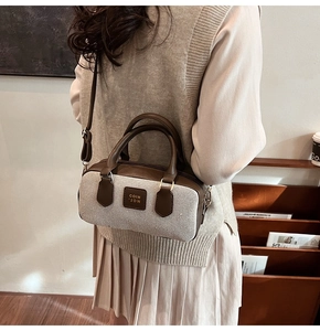 Detail of canvas bowling bag with brown leather trim worn as a crossbody bag by a model