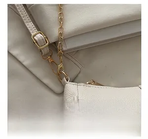 Close-up of golden metal hardware and beige lychee pattern leather texture on baguette bag