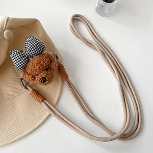 Détail de la lanière de téléphone tissée avec tête de chien en peluche et nœud à carreaux