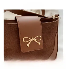 Detail of dark brown leather handbag with gold bow buckle and suede patchwork design