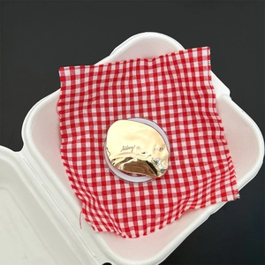 Detail view of gold mirror phone grip with 'happy' engraving on picnic cloth setup