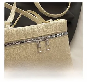 Detail view of the silver double zipper closure on cream pebble grain leather handbag