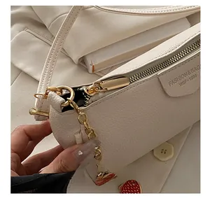 Detail of lychee pattern leather handbag with gold zipper and strawberry pendant