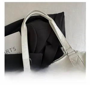 Detail of comfortable double straps on cream tote bag with metallic ring and stitching
