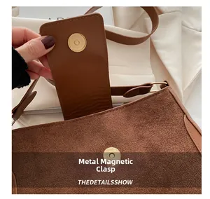Detail of golden magnetic clasp on brown suede and leather vintage shoulder bag
