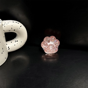Detailansicht der rosa Glitzer-Katzenpfote-Handyhalterung mit Herz auf schwarzem Lederhintergrund