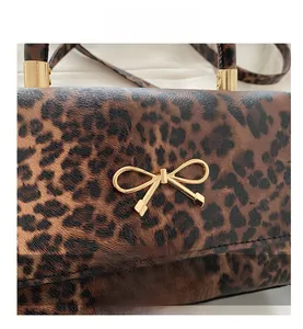 Close-up of leopard print handbag featuring a premium gold bow metal buckle and leather texture