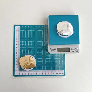 Irregular geometric metallic phone grips in gold and silver finish on a digital scale