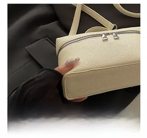 Detail view of cream-colored pebble leather texture and silver zipper on handbag