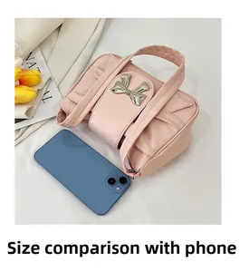 Mini sac à main plissé rose comparaison de taille avec smartphone sur fond souple