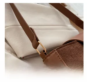 Detail of metal ring buckle and premium leather stitching on brown shoulder bag
