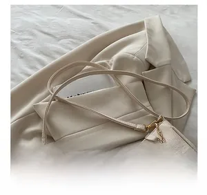 Detail of cream lychee leather texture with gold chain and adjustable shoulder strap