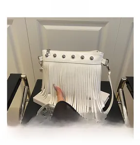 Détail du sac à bandoulière blanc à franges avec clous argentés sur un fauteuil chic