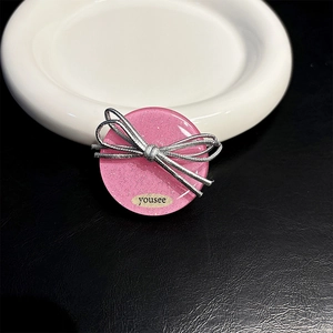 Detailed view of pink glitter resin phone grip with silver ribbon bow on ceramic plate