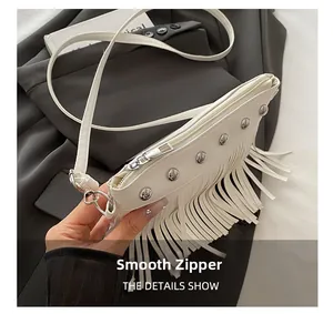 Détail de la fermeture éclair métallique lisse et des rivets sur le sac à franges blanc