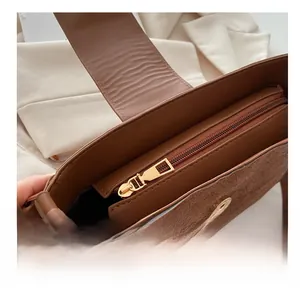 Macro detail of smooth golden metal zipper on brown leather and suede shoulder bag