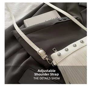 Détail d'un sac à bandoulière blanc avec rivets argentés, franges et sangle réglable