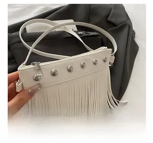 Détail du sac bandoulière blanc à franges avec rivets argentés et texture cuir lisse