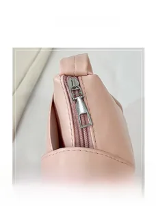 Gros plan d'une fermeture éclair en métal argenté sur un sac à bandoulière rose plissé